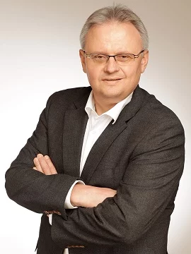 Ein Mann steht mit verschränkten Armen und blickt aufmerksam - bereit, Aufgaben im Betrieb anzupacken.