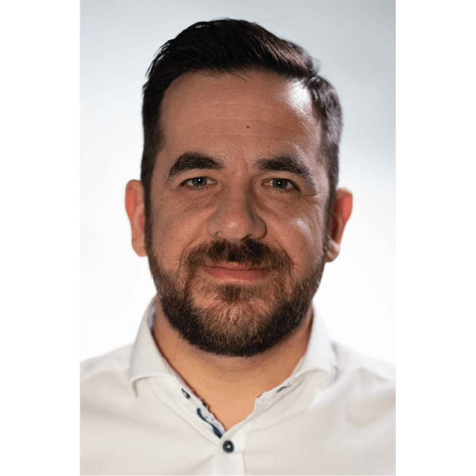 Ein Kollege lächelt freundlich in die Kamera - bereit für den nächsten Auftrag, der die Ärmel schon hochgekrempelt hat.