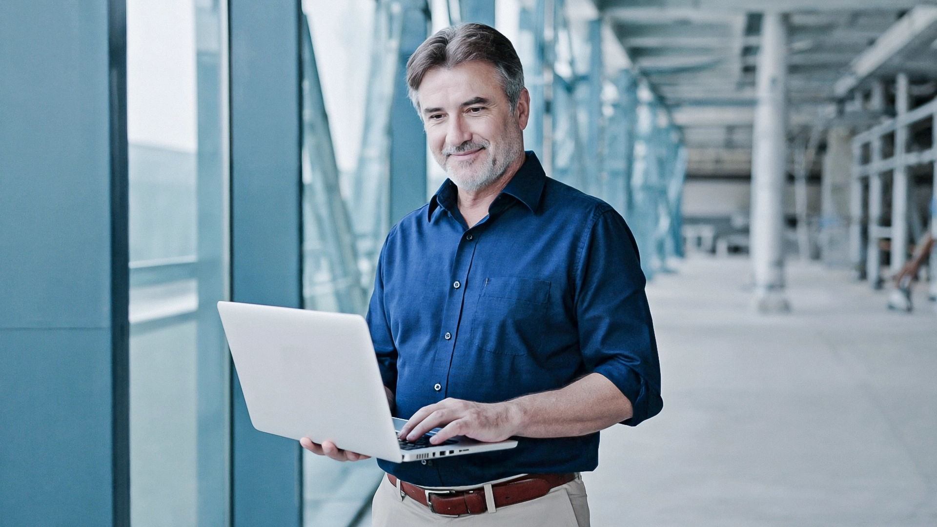 Ein Mann hält einen Laptop auf einer Innenbaustelle.